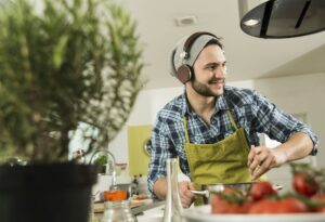 Young man with headphones cooking in kitchen at home